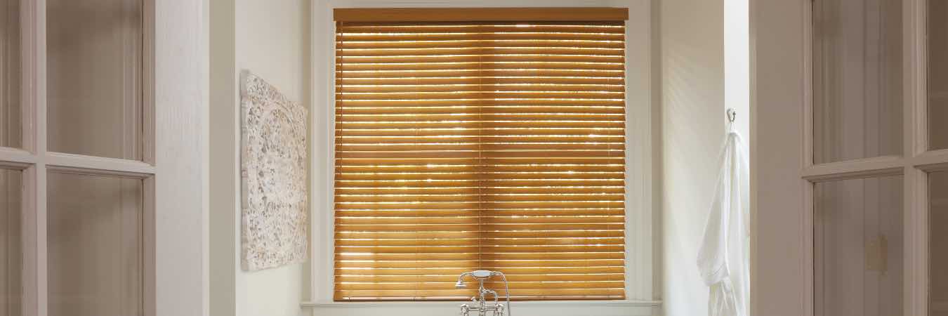 Brown faux wood blinds on a window over a bathtub